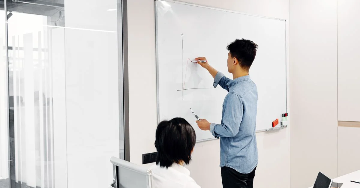 Profesional de negocios dibujando un gráfico durante una presentación de oficina con un colega
