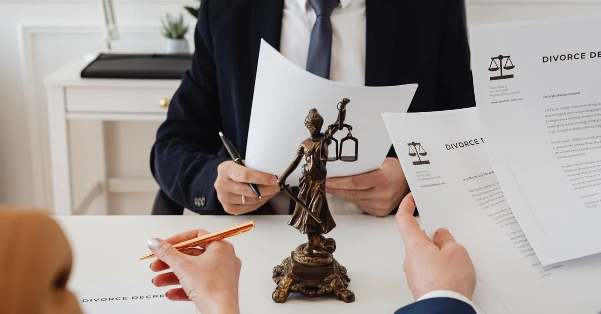Profesionales legales revisando documentos de divorcio en una oficina de abogados con una estatua de la Justicia.