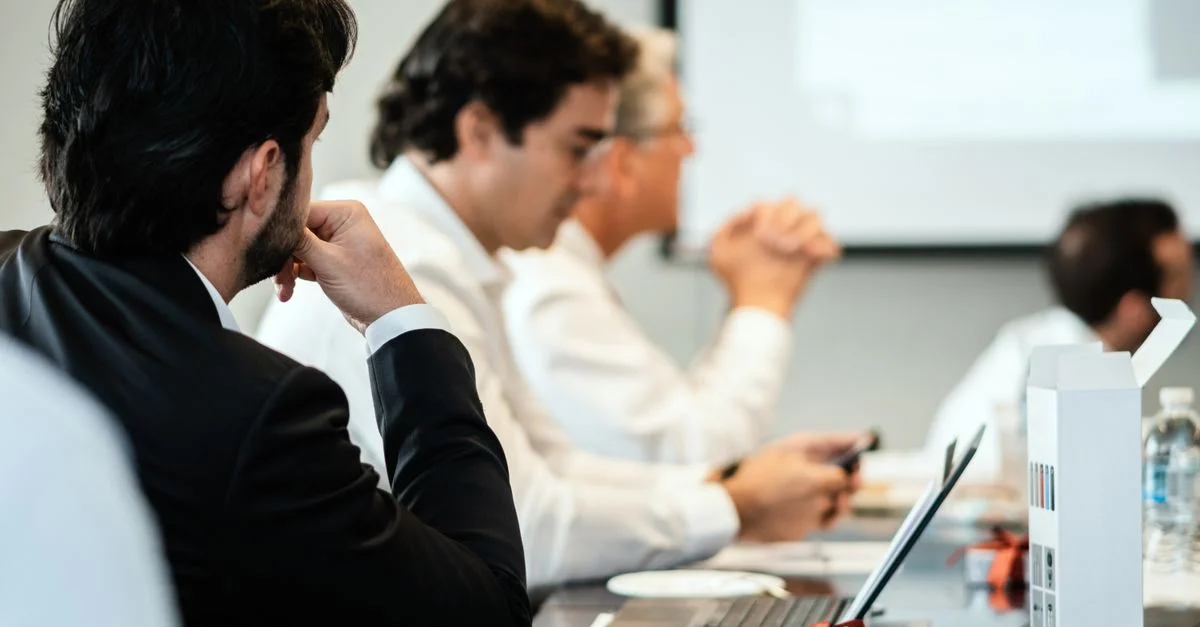 Profesionales corporativos en un entorno de reunión formal, centrados en el trabajo en equipo y la colaboración.