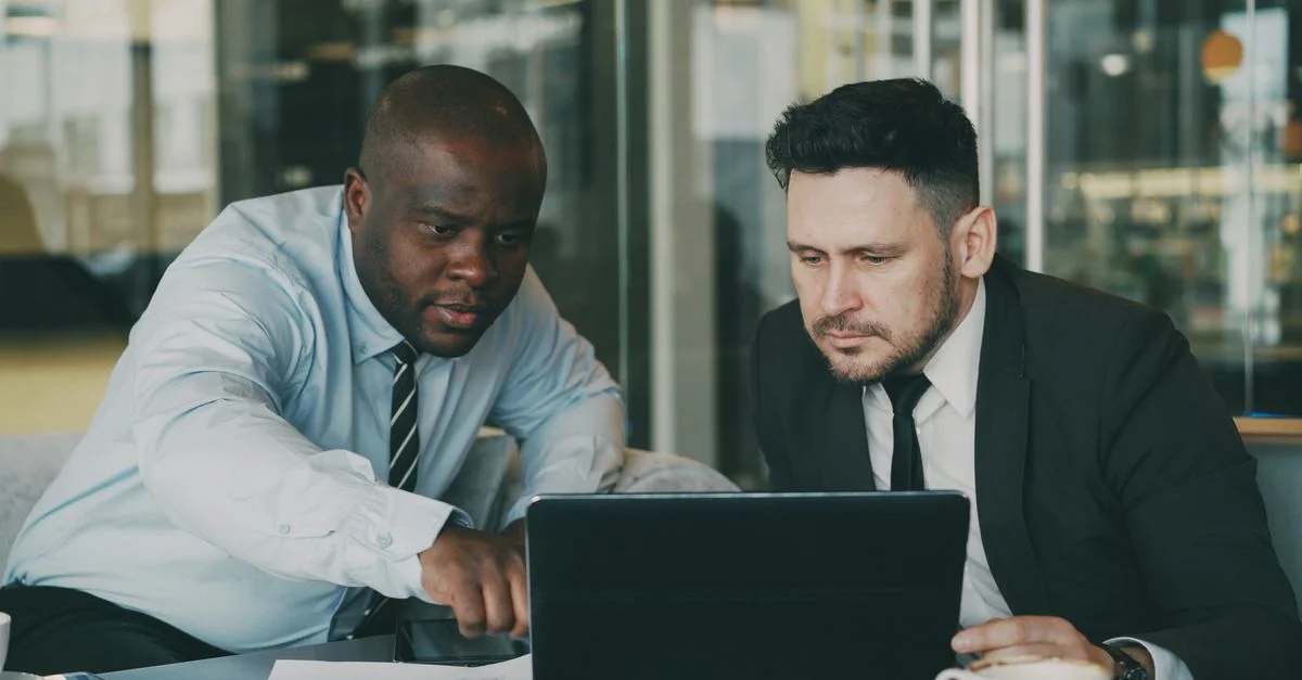 Dos empresarios concentrados en una tablet, colaborando en un entorno de oficina moderna.