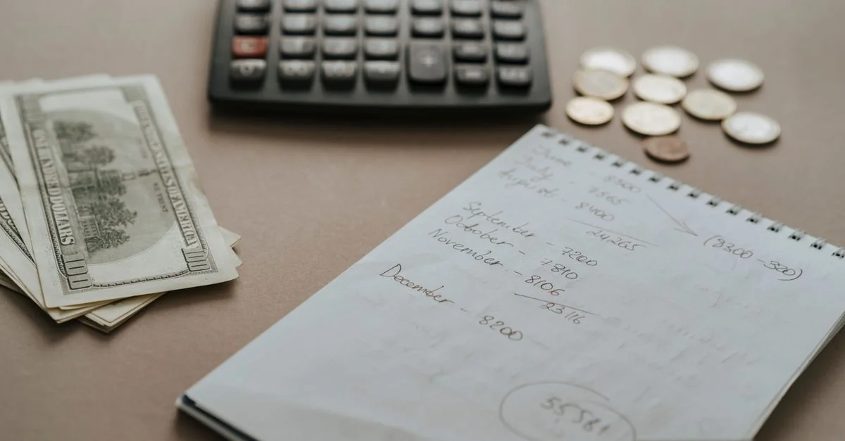 Configuración de escritorio que muestra una calculadora, dinero en efectivo, monedas y notas financieras para presupuestos.