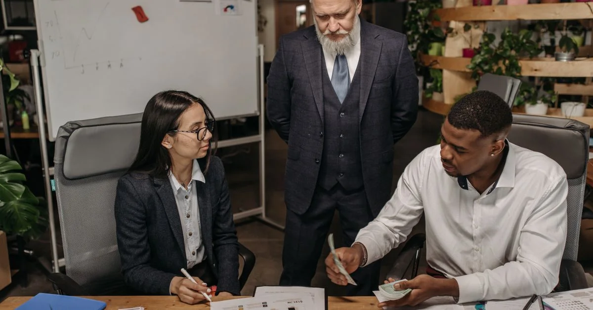 Tres profesionales de negocios discutiendo informes en un escritorio de oficina.