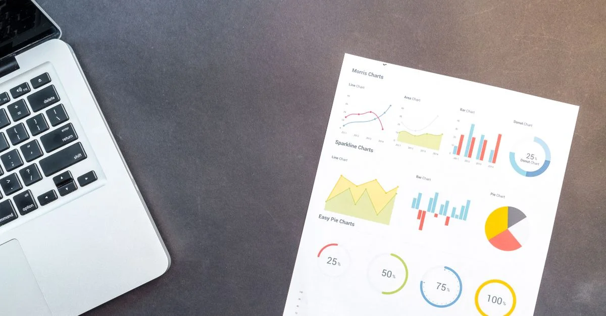 Configuración moderna de escritorio con un portátil y gráficos analíticos que muestran la interpretación de datos y el análisis de negocios.