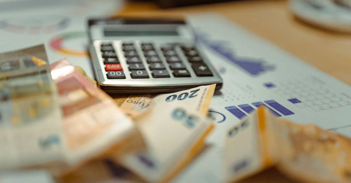 Billetes de euro y calculadora sobre documentos financieros, centrándose en la planificación del presupuesto empresarial.