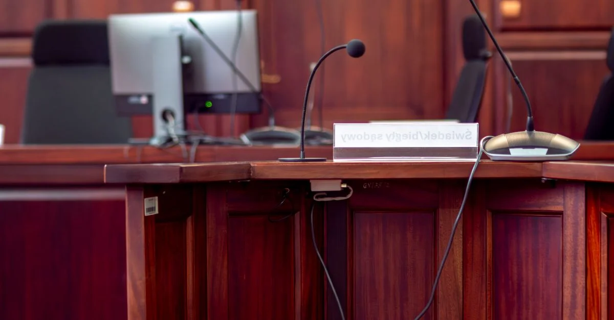 Primer plano de un podio de madera con micrófonos en un tribunal polaco.